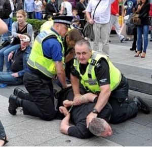 John Clayton restrained by police