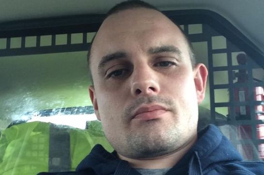 David Burnie takes a selfie in the back of a police car